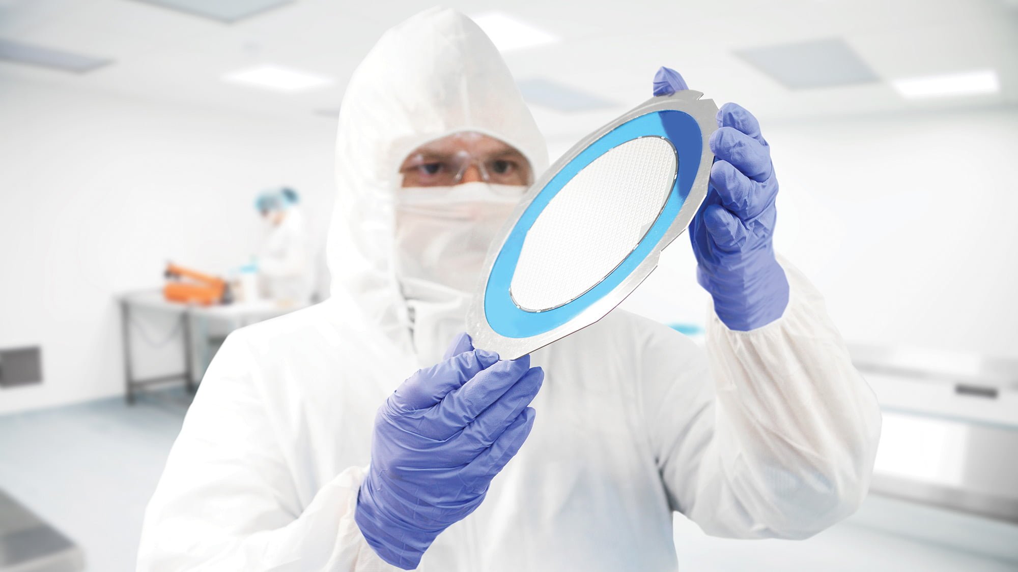 Photo of person in Cleanroom looking at a wafer